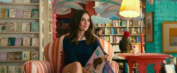 Movie still from “How to Be Single” (2016), directed by Christian Ditter – A woman sitting in a chair holding a book in her hands; Medium shot, Over the shoulder angle