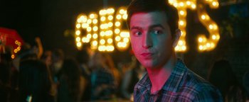 A young man in front of a lit up sign