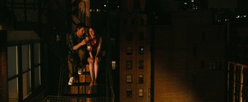 Movie still from “How to Be Single” (2016), directed by Christian Ditter – A man and a woman sitting on a fire escape at night; Wide shot, Overhead angle
