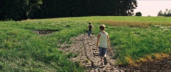 Movie still from “Goodnight Mommy” (2014), directed by Severin Fiala – Two young boys walking down a dirt path in a grassy field; Wide shot, High angle