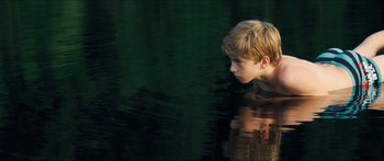 Movie still from “Goodnight Mommy” (2014), directed by Severin Fiala – A young boy swimming in a body of water; Medium shot, High angle