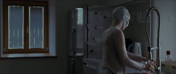Movie still from “Goodnight Mommy” (2014), directed by Severin Fiala – A woman wearing a head covering standing in front of an open refrigerator; Medium shot, Over the shoulder angle
