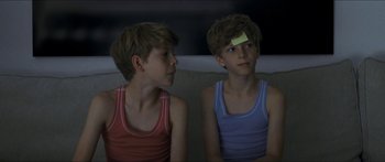 Movie still from “Goodnight Mommy” (2014), directed by Severin Fiala – Two young boys sitting on a couch with a post it note on their forehead; Close Up shot, Over the shoulder angle