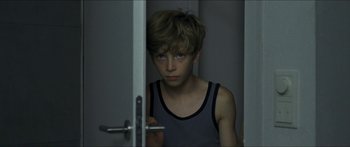 Movie still from “Goodnight Mommy” (2014), directed by Severin Fiala – A young boy standing in front of a door; Medium shot, Over the shoulder angle