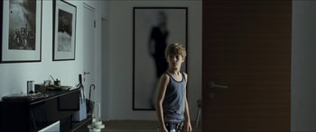 Movie still from “Goodnight Mommy” (2014), directed by Severin Fiala – A boy standing in front of a picture in a room; Medium shot, Over the shoulder angle