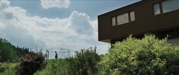 Movie still from “Goodnight Mommy” (2014), directed by Severin Fiala – A man standing in a field next to a building; Extreme Wide shot, Low angle