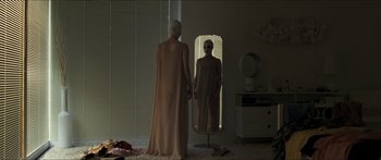 Movie still from “Goodnight Mommy” (2014), directed by Severin Fiala – A woman in a long dress standing in front of a mirror; Medium shot, Over the shoulder angle