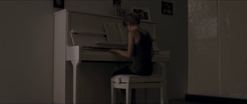 Movie still from “Goodnight Mommy” (2014), directed by Severin Fiala – A woman sitting on a chair playing the piano; Wide shot, High angle