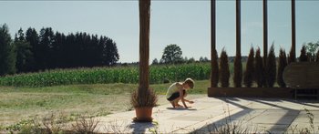 Movie still from “Goodnight Mommy” (2014), directed by Severin Fiala – A woman kneeling on the ground near a plant; Extreme Wide shot, High angle