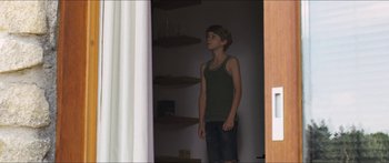 Movie still from “Goodnight Mommy” (2014), directed by Severin Fiala – A young man standing in a room with a door open; Medium shot, Low angle