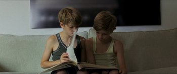 Movie still from “Goodnight Mommy” (2014), directed by Severin Fiala – Two young boys sitting on a couch looking at a book; Medium shot, High angle
