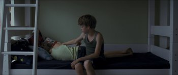Movie still from “Goodnight Mommy” (2014), directed by Severin Fiala – A boy sitting on a bed looking at a book; Medium shot, Over the shoulder angle