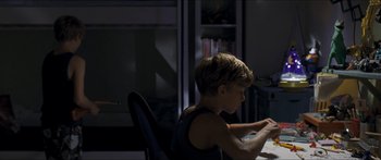 Movie still from “Goodnight Mommy” (2014), directed by Severin Fiala – A young boy sitting at a table in a dark room; Medium shot, High angle