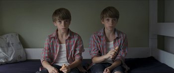 Movie still from “Goodnight Mommy” (2014), directed by Severin Fiala – Two identical boys sitting on a couch holding bananas; Close Up shot, High angle