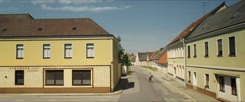 Movie still from “Goodnight Mommy” (2014), directed by Severin Fiala – A person riding a bike down a street; Extreme Wide shot, High angle
