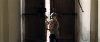 Movie still from “Goodnight Mommy” (2014), directed by Severin Fiala – A young boy standing in front of an open door; Medium shot, Over the shoulder angle