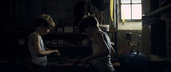 Movie still from “Goodnight Mommy” (2014), directed by Severin Fiala – A young man working in a shop with tools on a table; Medium shot, Over the shoulder angle