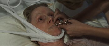 Movie still from “Goodnight Mommy” (2014), directed by Severin Fiala – A woman is getting her face waxed by a person with scissors; Close Up shot, High angle