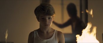 Movie still from “Goodnight Mommy” (2014), directed by Severin Fiala – A young boy in a white tank top stares at the camera; Close Up shot, Over the shoulder angle