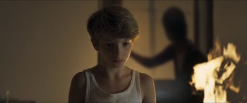 Movie still from “Goodnight Mommy” (2014), directed by Severin Fiala – A young boy in a white tank top looking at the camera; Close Up shot, Over the shoulder angle