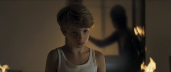 Movie still from “Goodnight Mommy” (2014), directed by Severin Fiala – A young boy in a white tank top looking at the camera; Close Up shot, Over the shoulder angle