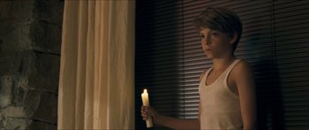 Movie still from “Goodnight Mommy” (2014), directed by Severin Fiala – A young boy holding a lit candle in front of a window; Medium shot, Over the shoulder angle