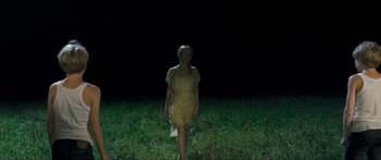 Movie still from “Goodnight Mommy” (2014), directed by Severin Fiala – A woman standing in the grass at night; Wide shot, High angle