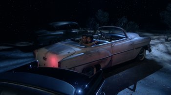Movie still from “Grease Live!” (2016), directed by Thomas Kail – Two people in the back of an old car; Wide shot, High angle