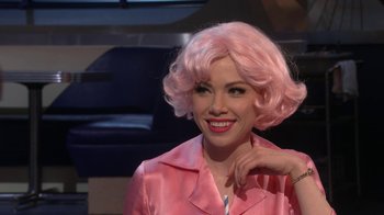 Movie still from “Grease Live!” (2016), directed by Thomas Kail – A woman in a pink wig posing for a picture; Close Up shot, Over the shoulder angle