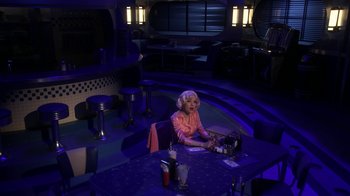 Movie still from “Grease Live!” (2016), directed by Thomas Kail – A woman sitting at a table in a restaurant; Wide shot, High angle