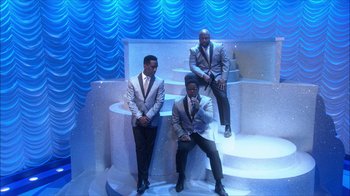 Movie still from “Grease Live!” (2016), directed by Thomas Kail – A group of men in suits posing for a picture; Wide shot, High angle