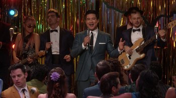Movie still from “Grease Live!” (2016), directed by Thomas Kail – A group of men in suits and bow ties singing; Medium shot, Over the shoulder angle