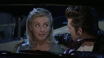Movie still from “Grease Live!” (2016), directed by Thomas Kail – A man and a woman are looking at each other in a car; Close Up shot, Over the shoulder angle