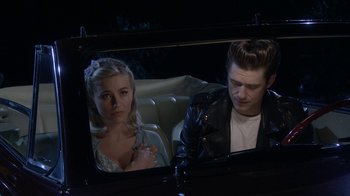 Movie still from “Grease Live!” (2016), directed by Thomas Kail – A man and a woman sitting in the back seat of a car; Medium shot, Over the shoulder angle