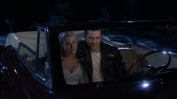 Movie still from “Grease Live!” (2016), directed by Thomas Kail – A man and a woman in the back seat of a car; Medium shot, Over the shoulder angle