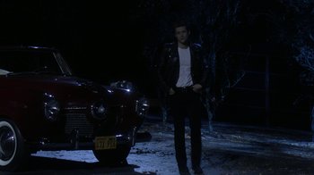 Movie still from “Grease Live!” (2016), directed by Thomas Kail – A man standing in front of a car at night; Wide shot, Low angle