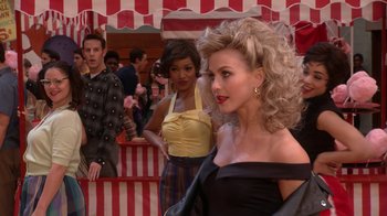 Movie still from “Grease Live!” (2016), directed by Thomas Kail – A group of women standing next to each other in a room; Medium shot, Over the shoulder angle