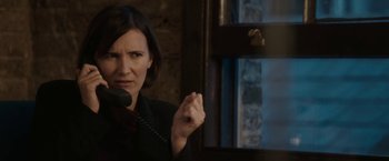 Movie still from “Greed” (2019), directed by Michael Winterbottom – A woman holding a phone up to her ear; Close Up shot, Over the shoulder angle