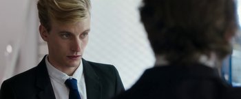 Movie still from “Greed” (2019), directed by Michael Winterbottom – A man in a suit and tie talking to another man in a suit and tie; Close Up shot, Over the shoulder angle