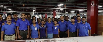 Movie still from “Greed” (2019), directed by Michael Winterbottom – A group of people standing in front of a table; Wide shot, High angle