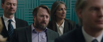 Movie still from “Greed” (2019), directed by Michael Winterbottom – A man and a woman sitting next to each other; Close Up shot, Over the shoulder angle