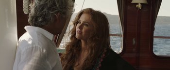 Movie still from “Greed” (2019), directed by Michael Winterbottom – A woman with long red hair and a man with long white hair on a boat in the ocean; Close Up shot, Over the shoulder angle