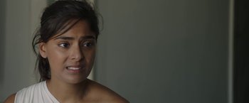 Movie still from “Greed” (2019), directed by Michael Winterbottom – A woman's face in a room; Close Up shot, Over the shoulder angle