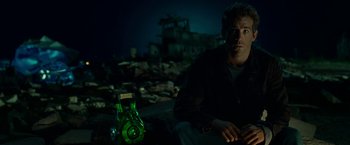 Movie still from “Green Lantern” (2011), directed by Martin Campbell – A man sitting on the ground next to a bottle; Medium shot, Low angle
