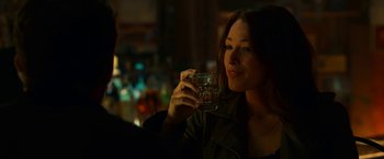 Movie still from “Green Lantern” (2011), directed by Martin Campbell – A woman holding a glass of water in her hand; Close Up shot, Over the shoulder angle