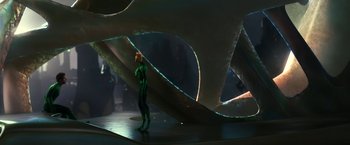 Movie still from “Green Lantern” (2011), directed by Martin Campbell – A man in a green suit standing in front of an abstract sculpture; Wide shot, Over the shoulder angle