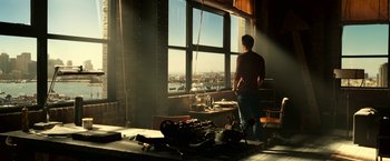 Movie still from “Green Lantern” (2011), directed by Martin Campbell – A man looking out of a large window at a city; Wide shot, Low angle
