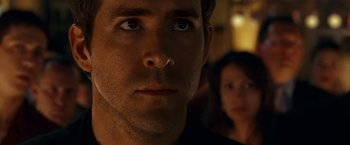 Movie still from “Green Lantern” (2011), directed by Martin Campbell – A man's face and a woman in the background; Close Up shot, Over the shoulder angle