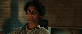 Movie still from “Green Lantern” (2011), directed by Martin Campbell – A man with curly hair wearing glasses and a plaid shirt; Close Up shot, Over the shoulder angle
