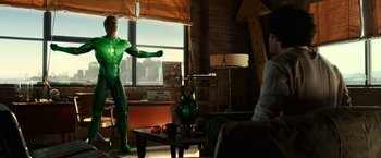 Movie still from “Green Lantern” (2011), directed by Martin Campbell – A man dressed in a green costume stands in a living room; Wide shot, Over the shoulder angle